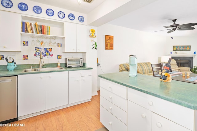 kitchen with sink, stainless steel dishwasher, decorative backsplash, light wood-type flooring, and white cabinetry