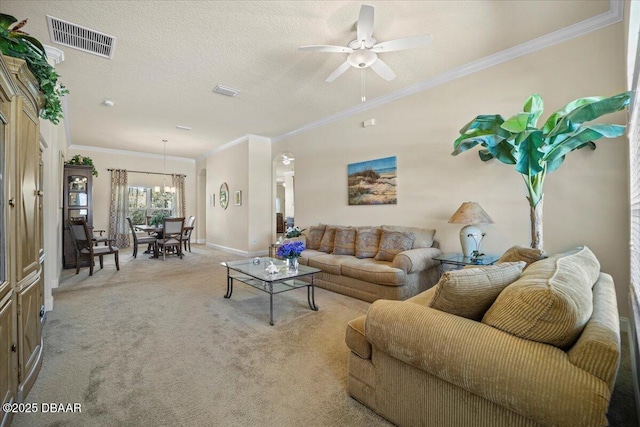 carpeted living room with a textured ceiling, ceiling fan with notable chandelier, visible vents, baseboards, and crown molding