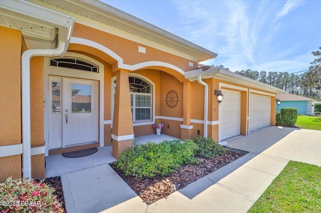 property entrance with driveway, an attached garage, and stucco siding