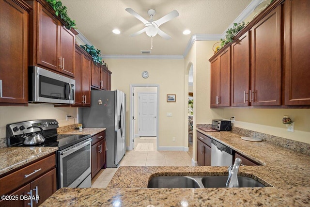 kitchen with ceiling fan, light stone counters, stainless steel appliances, visible vents, and ornamental molding