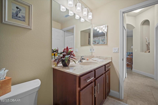 bathroom featuring toilet, tile patterned floors, baseboards, and vanity