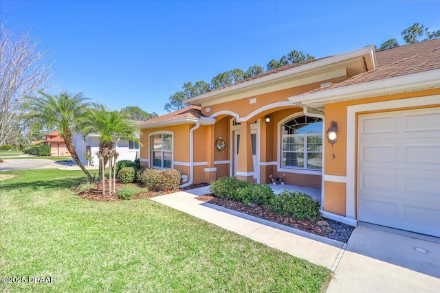 view of front of property featuring a garage, a front yard, and stucco siding