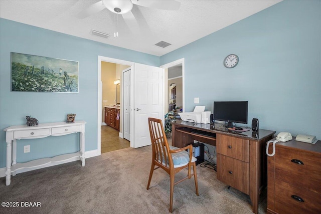 office space featuring a textured ceiling, carpet, visible vents, and a ceiling fan