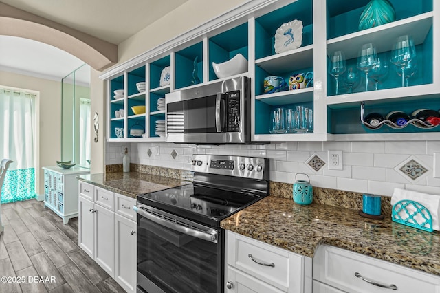 kitchen with white cabinets, stainless steel appliances, dark stone counters, and tasteful backsplash