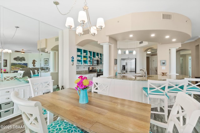 dining room with ceiling fan with notable chandelier, wood-type flooring, and sink