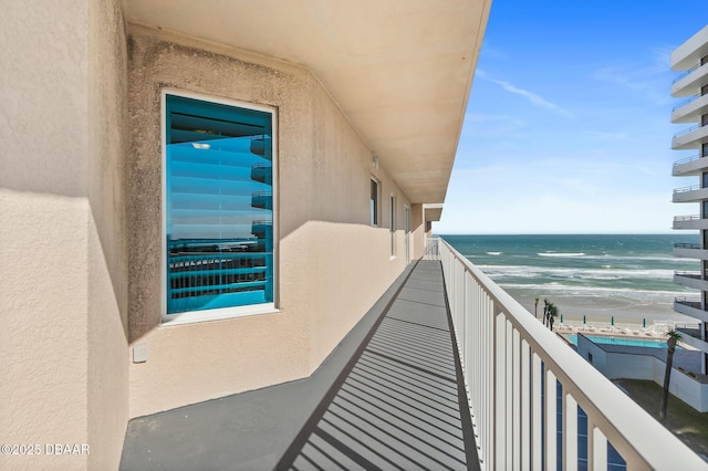 balcony featuring a view of the beach and a water view