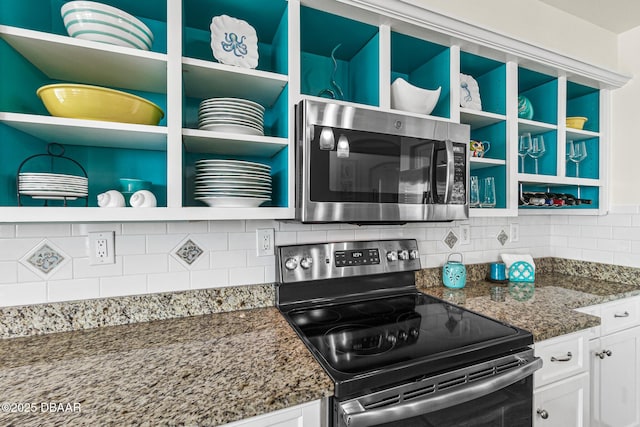 kitchen with appliances with stainless steel finishes, white cabinetry, dark stone countertops, and decorative backsplash