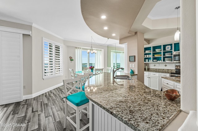 kitchen featuring sink, decorative light fixtures, white cabinetry, and stone countertops