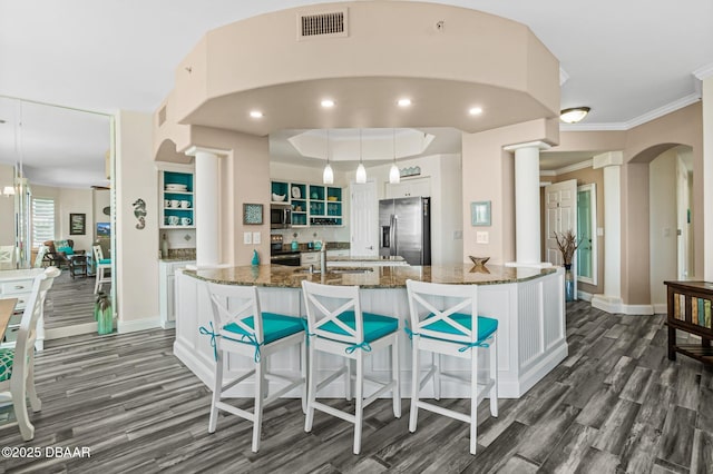 kitchen with pendant lighting, a center island with sink, white cabinets, dark stone counters, and appliances with stainless steel finishes