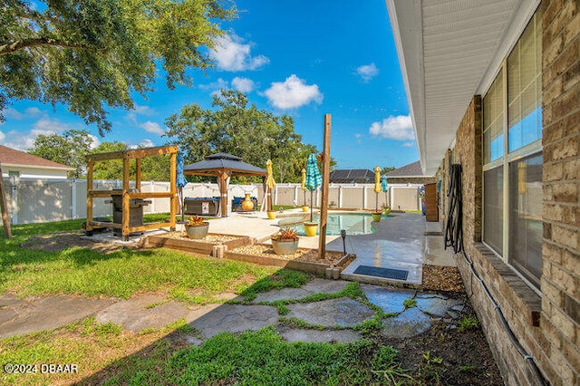 view of yard featuring a fenced in pool, a patio, and a gazebo