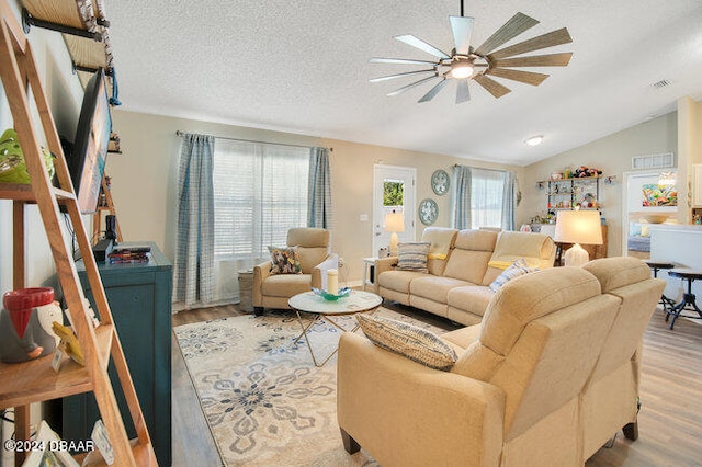 living room with vaulted ceiling, light hardwood / wood-style floors, and plenty of natural light