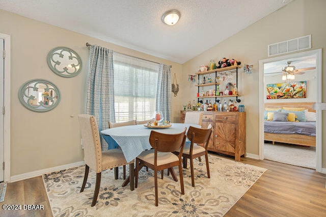 dining space with hardwood / wood-style flooring, ceiling fan, a textured ceiling, and vaulted ceiling