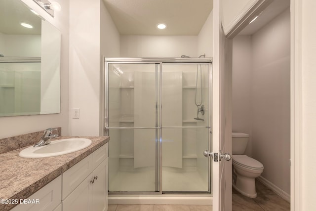 bathroom with toilet, tile patterned flooring, a shower with door, and vanity