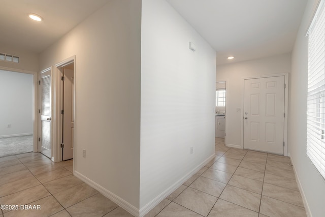 hallway with washer / clothes dryer and light tile patterned floors