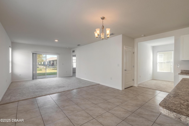 carpeted empty room featuring an inviting chandelier