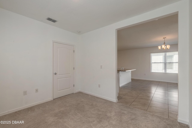 spare room with light colored carpet and a chandelier