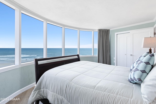 bedroom with multiple windows, a water view, hardwood / wood-style flooring, and crown molding