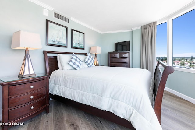bedroom with visible vents, baseboards, ornamental molding, and wood finished floors