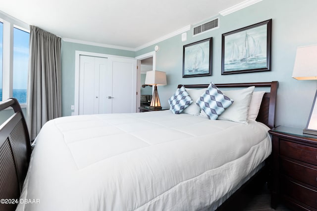 bedroom with a closet, a water view, and crown molding