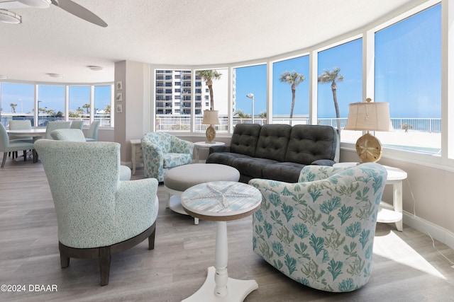 living room featuring light wood-type flooring, a water view, and plenty of natural light