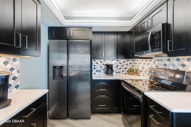 kitchen with appliances with stainless steel finishes, crown molding, a tray ceiling, and light hardwood / wood-style flooring