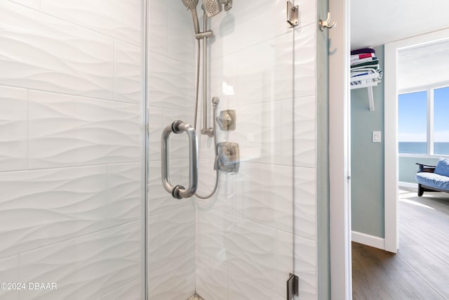 bathroom featuring hardwood / wood-style floors, a shower with door, and a water view