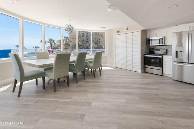 dining area featuring a wealth of natural light, a textured ceiling, a notable chandelier, and a water view