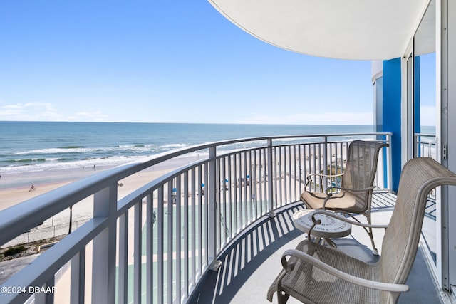 balcony featuring a view of the beach and a water view