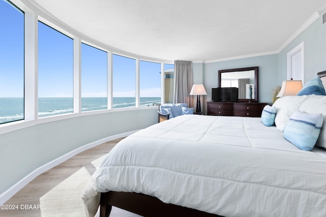 bedroom featuring light hardwood / wood-style floors, a water view, a beach view, and ornamental molding