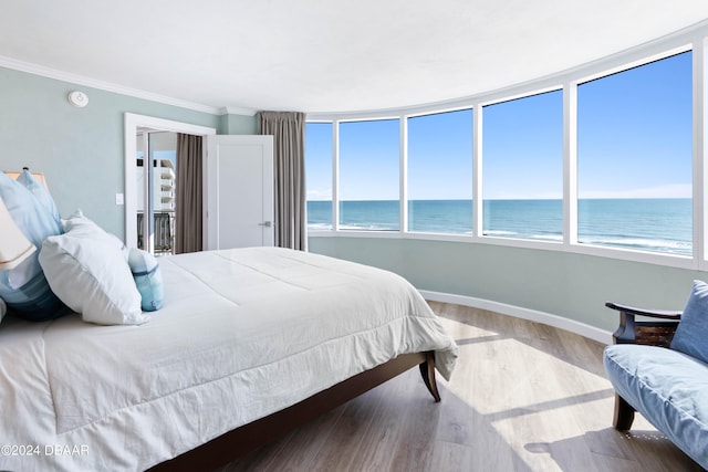 bedroom with a beach view, a water view, crown molding, and wood-type flooring