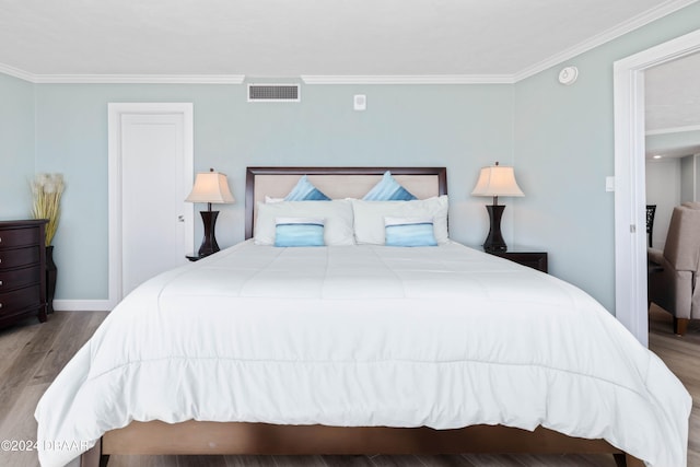 bedroom with ornamental molding and light hardwood / wood-style floors