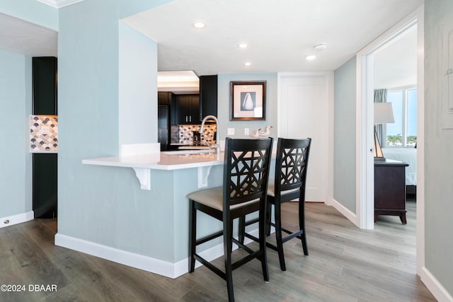 kitchen with kitchen peninsula, tasteful backsplash, sink, and light wood-type flooring