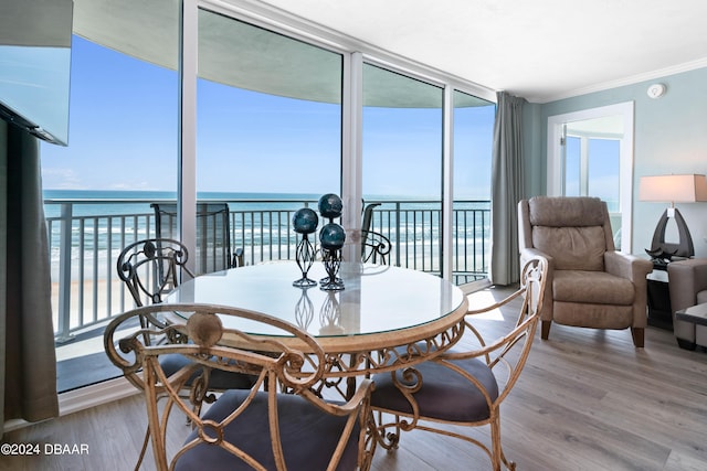 dining room featuring expansive windows, hardwood / wood-style flooring, a water view, and ornamental molding