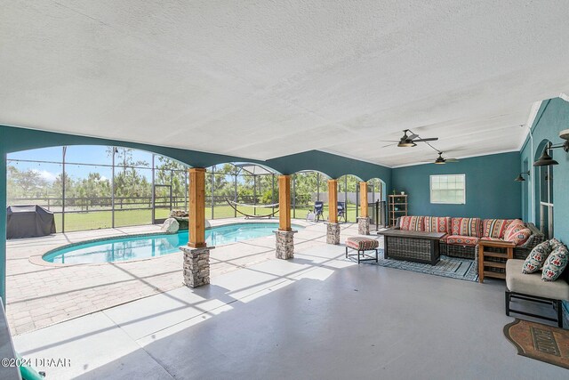 view of pool with glass enclosure, a patio area, outdoor lounge area, and ceiling fan