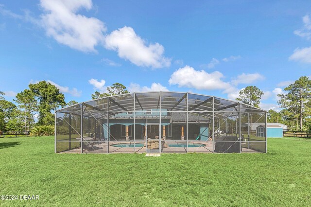 rear view of property featuring a patio, a lawn, a lanai, and a swimming pool with hot tub