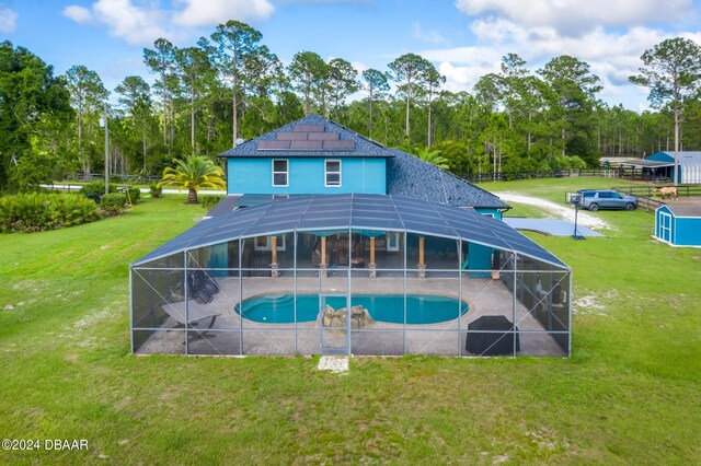 view of pool featuring a yard, glass enclosure, and a patio area