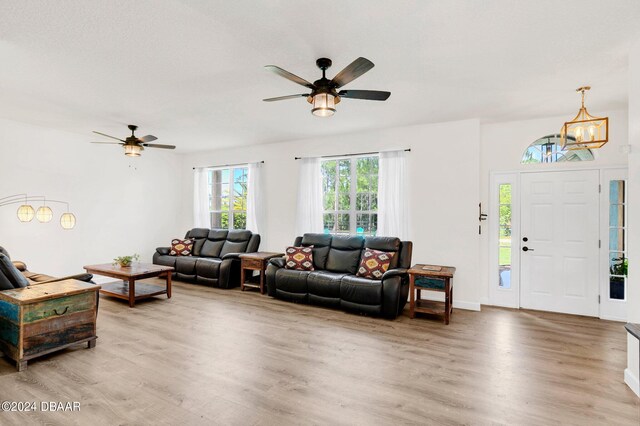 living room with ceiling fan with notable chandelier and wood-type flooring