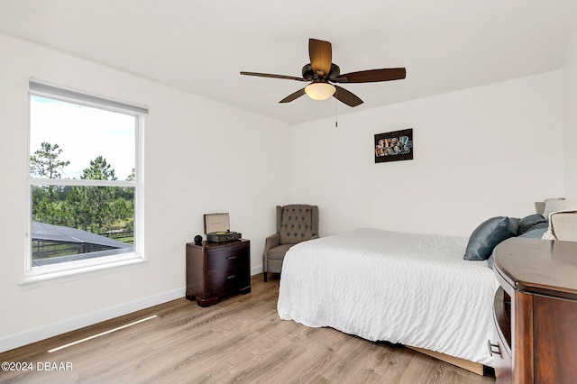 bedroom featuring ceiling fan, multiple windows, and light hardwood / wood-style flooring