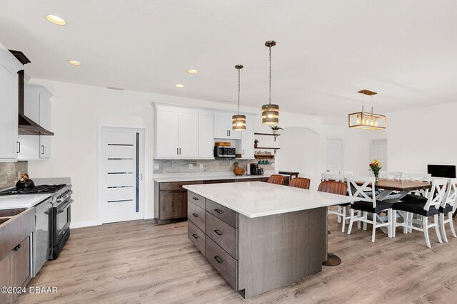 kitchen featuring stainless steel appliances, a kitchen island, a kitchen bar, pendant lighting, and light hardwood / wood-style floors