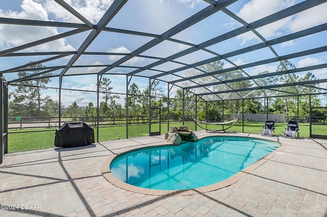 view of swimming pool with glass enclosure, a patio, and a yard