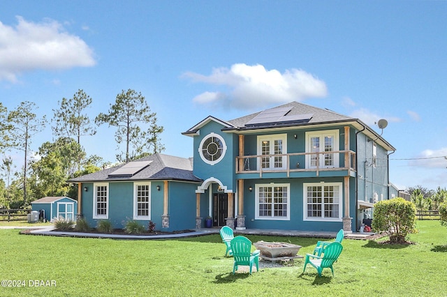 rear view of house with a storage unit, solar panels, and a yard