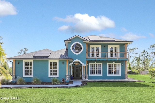 view of front of house with french doors, solar panels, a front yard, and a balcony