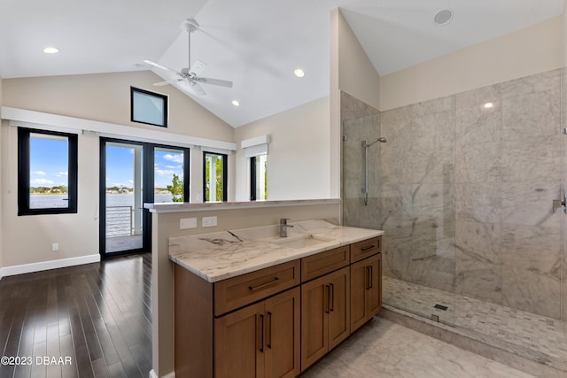 bathroom with ceiling fan, hardwood / wood-style floors, vanity, tiled shower, and vaulted ceiling