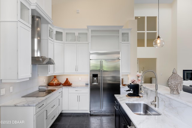 kitchen with black electric cooktop, sink, hanging light fixtures, built in refrigerator, and white cabinets