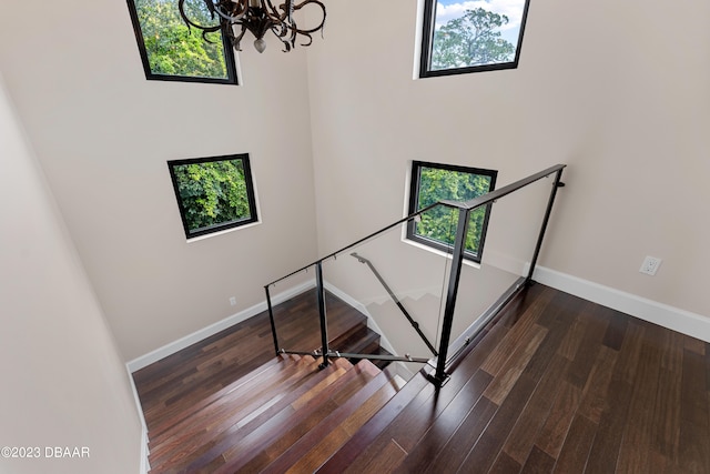 stairway featuring hardwood / wood-style floors, a healthy amount of sunlight, and a chandelier