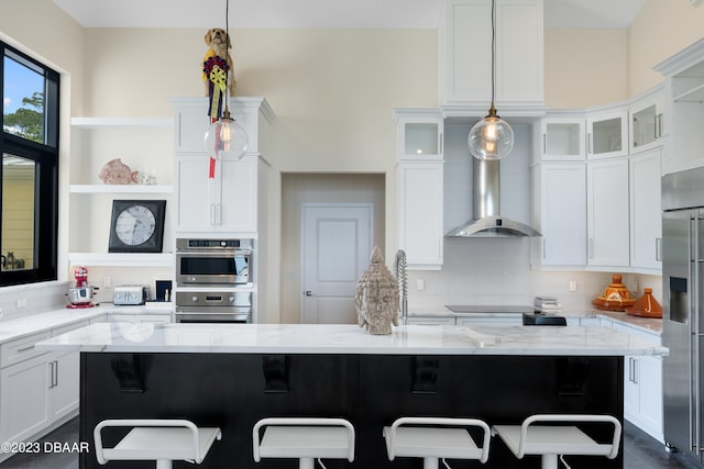 kitchen with pendant lighting, appliances with stainless steel finishes, light stone countertops, and a kitchen breakfast bar