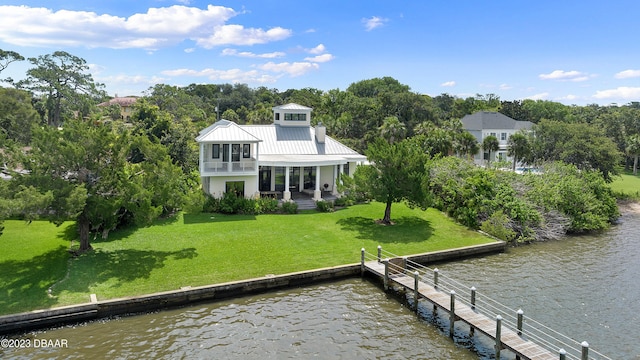 rear view of house with a water view and a lawn