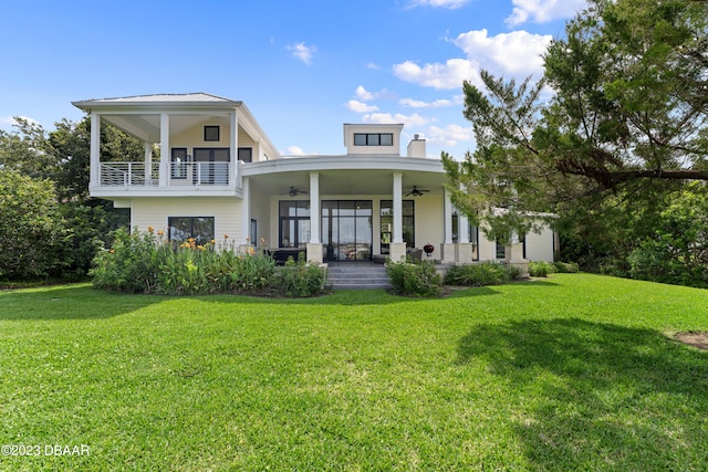 rear view of property featuring a lawn, a balcony, and ceiling fan