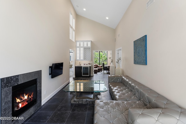 living room with a towering ceiling and a tiled fireplace