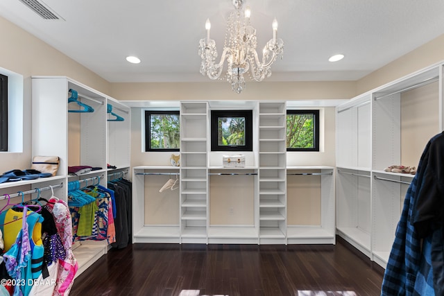 walk in closet featuring dark hardwood / wood-style flooring and a notable chandelier